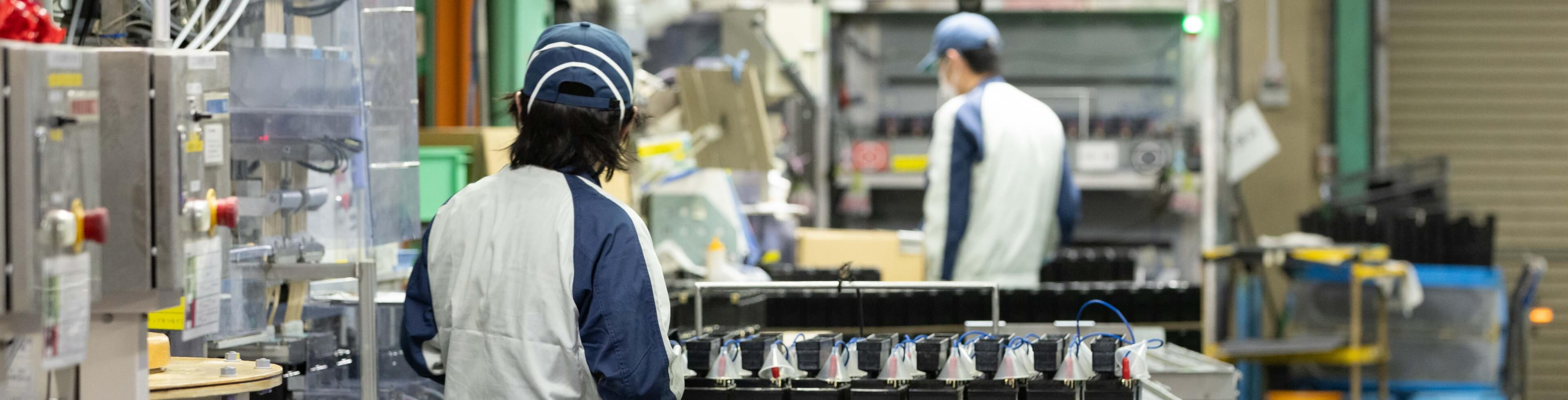 工場の機械の前で作業をしている社員